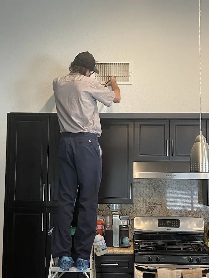 Technician inspecting an air vent during HVAC service in Albion
